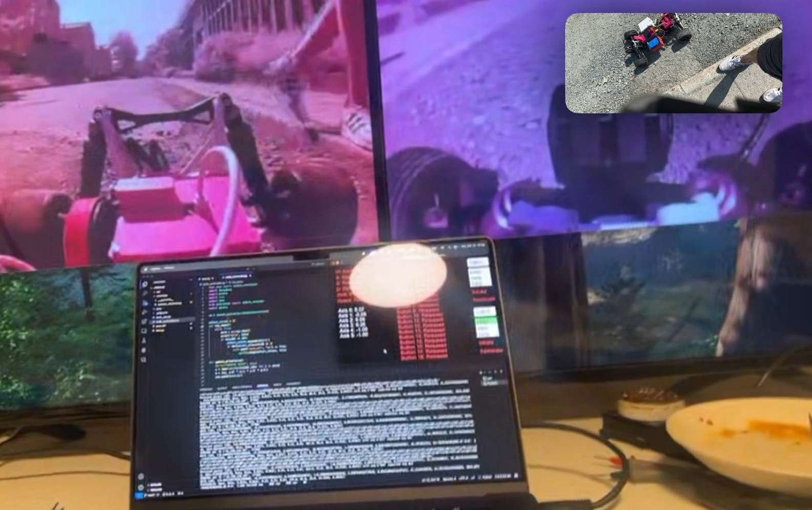 Førerstasjonen under kjøring: to store skjermer over en laptop, hver skjerm viser ett av bilens to kameraer (en lav frontvisning ned en vei og en bredere oversiktsvisning). Et bilde-i-bilde-overlegg i hjørnet viser den faktiske RC-bilen på asfalten ved siden av en sko. Laptopskjermen er delt mellom kode til venstre og live telemetri (styring, gass, akseverdier) til høyre.