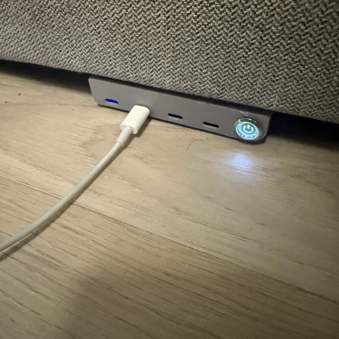 Den samme stasjonen med av/på-knappen lyst opp i blått og en portindikator som gløder, en kabel koblet i.