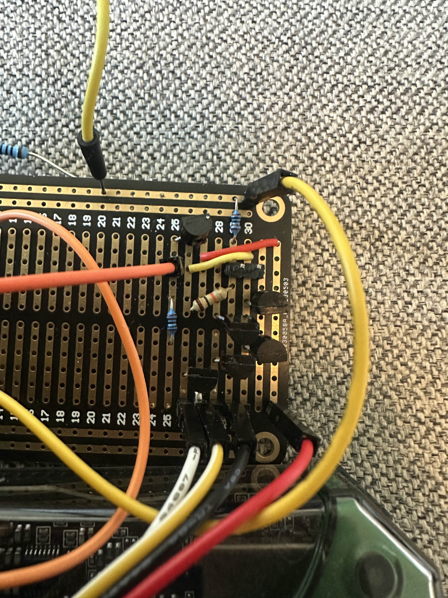Den diskrete op-amp-en bygget på et veroboard. Seks småsignaltransistorer presset inn i et hjørne med en floke av røde, gule, oransje og svarte ledninger som går til koblingsbrettet under.