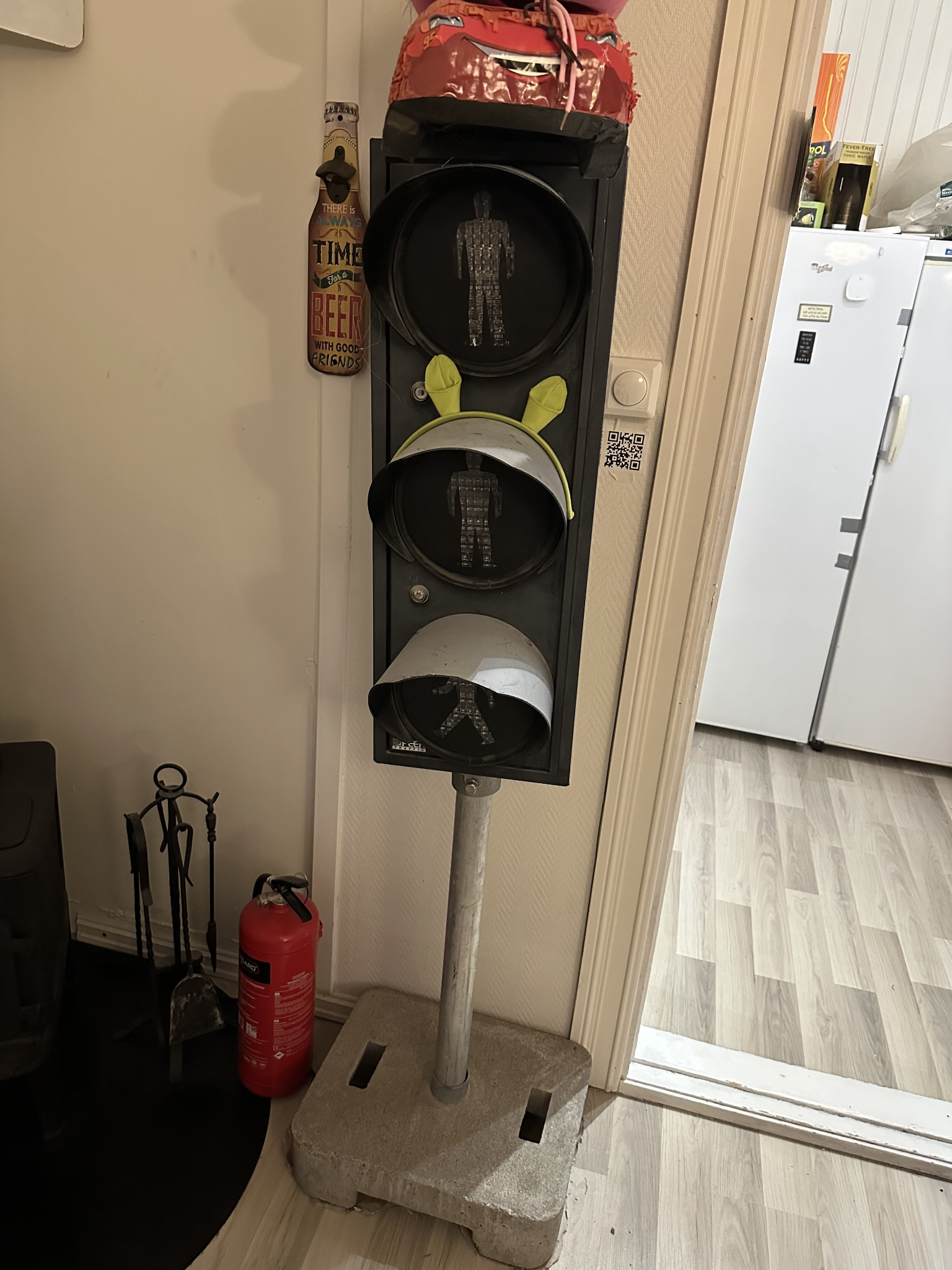 The pedestrian traffic light standing in the kitchen, unlit. Three stacked lamp housings on a concrete base.